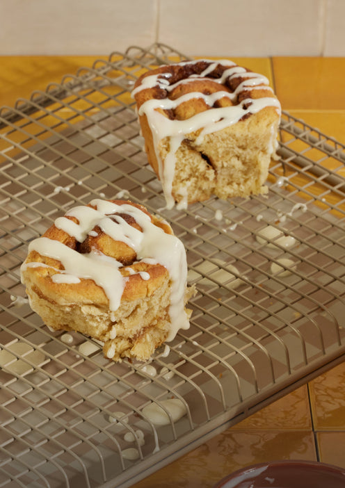 Cinnamon rolls cooking on a beige Oven Rack