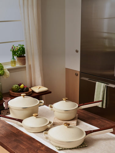 Set of ceramic cookware on a kitchen counter with a towel and books in the background.