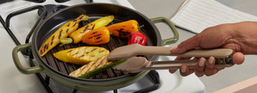 Person grilling vegetables in a pan on a stove