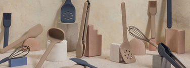 Set of kitchen utensils including spatulas, ladles, and whisks on a neutral background