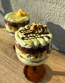 Two layered dessert in glass cups on a wooden surface with a neutral background