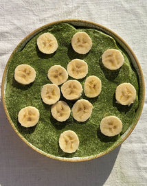 Green match pudding with sliced bananas on a textured surface