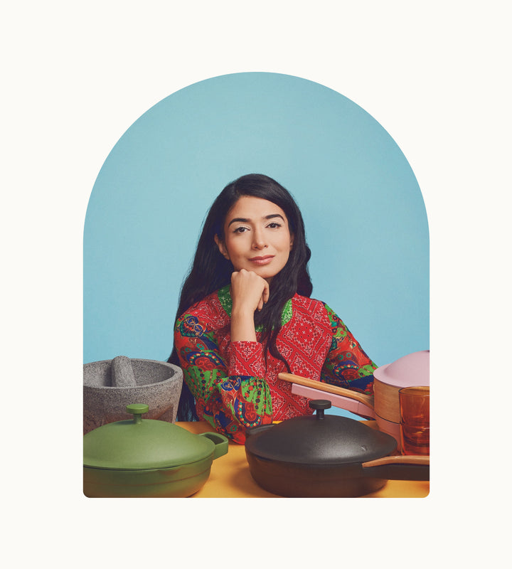 Shiza Shahid sitting at a table with cookware, against a blue background