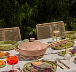 Dining table set with a pink ceramic dish, glasses, and plates outdoors.