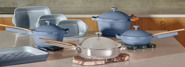 Set of blue cookware on a kitchen counter with wooden cabinets in the background