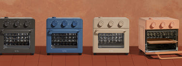 Four small ovens in different colors on a red background