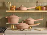 Set of pink cookware on a kitchen counter with green tiled wall in the background