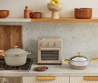 Kitchen scene with a stove, oven, and various cookware on a countertop.