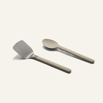 Titanium Pro Utensil Set containing a stainless steel metal spatula and a matching solid-colored serving spoon.
