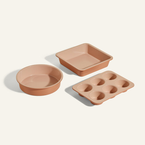 The Wonder Oven Baker's Kit features three non-toxic beige pans—a round cake pan, a square pan, and a six-cup muffin tray—arranged on a light background, making them ideal for your Wonder Oven.