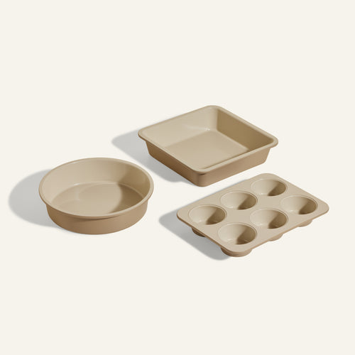 The Wonder Oven Baker's Kit includes three beige non-toxic pans: a round cake pan, a square baking pan, and a six-cup muffin tin—ideal for your Wonder Oven.