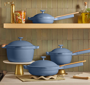 Set of blue cookware on a kitchen shelf with a green tiled wall background