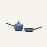 The Tiny Cookware Duo, featuring a blue non-toxic saucepan with lid and a matching frying pan inspired by the Always Pan and Perfect Pot, is displayed side by side on a light background.