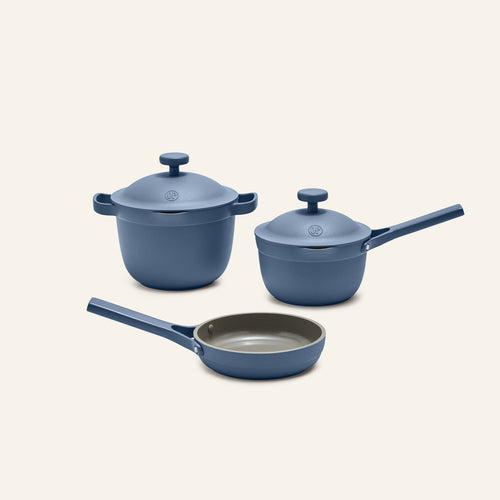 The Tiny Cookware Duo + Petite Perfect Pot is a three-piece blue set featuring a stock pot, a saucepan with lids, and a frying pan with matching handles, all displayed on a plain light background.