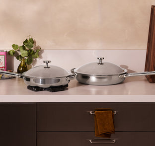 Two titanium pans on a kitchen counter with a neutral background.