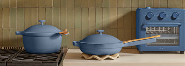Blue cookware set with a matching oven on a wooden surface.