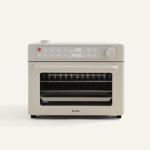 The Wonder Oven Pro is a beige countertop mini oven and air fryer with digital controls, display screen, and multiple racks by Our Place.
