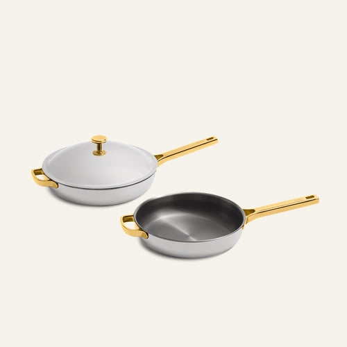 Titanium Pro Always Pan Duo (2.0) featuring two white stainless steel pans with gold-tone handles, one with a matching lid.
