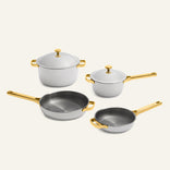 Titanium Pro Cookware Set (2.0) consisting of two light gray titanium pots with lids and two matching frying pans, all featuring polished gold handles.
