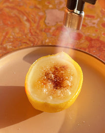 Half of a lemon being brulee on a pink plate
