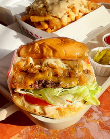 Double cheeseburger with fries and condiments in a fast-food setting