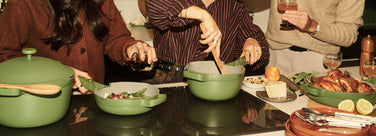 People gathered around a table with green pots, food, and drinks.