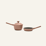 The Tiny Cookware Duo, featuring a pink non-toxic Perfect Pot with lid and a matching frying pan, is displayed side by side against a plain light background.