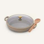 Ceramic Nonstick Dual Handle Always Pan 32 cm with beige finish, glass lid with gold knob, and a wooden spoon—stylish, versatile cookware on a plain background.