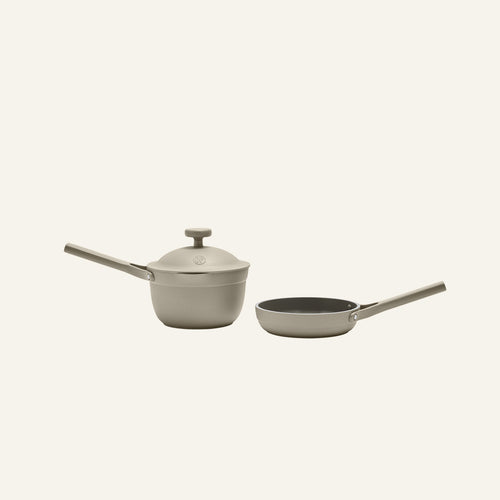 The Tiny Cookware Duo, featuring a beige Perfect Pot with lid and matching Always Pan—both non-toxic with long handles—is displayed on a plain light background.